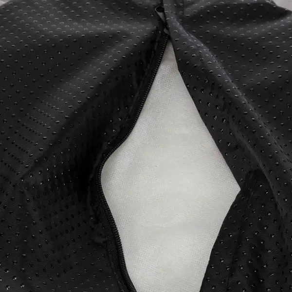 Detalle de tejido técnico transpirable en negro con cremallera, mostrando la capa interior de acolchado para ropa deportiva o equipamiento de alto rendimiento