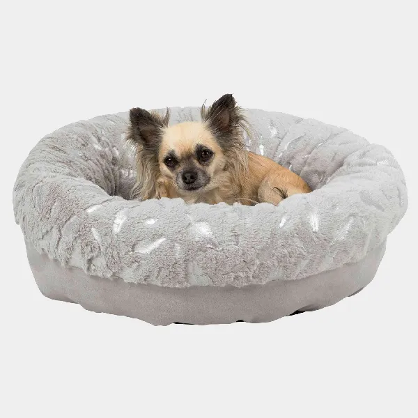 Pequeño perro Chihuahua disfrutando de una cama redonda y acolchada para perros pequeños con tejido de felpa gris y detalles brillantes, asegurando un descanso cómodo y estilizado