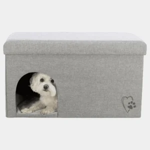 Perro pequeño relajado dentro de una cueva moderna con cojín extraíble para perros pequeños en color gris, decorada con un corazón y una huella