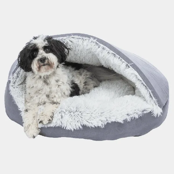 Perro pequeño y sonriente descansando en una cueva iglú de peluche gris para perros pequeños, mostrando comodidad y estilo