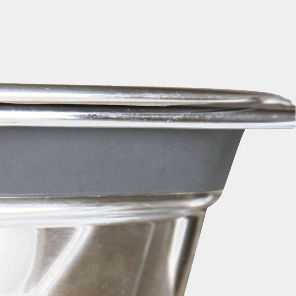 Primer plano de la esquina de un comedero de acero inoxidable con soporte, mostrando la calidad y el acabado del material resistente y duradero para mascotas