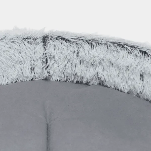 Primer plano del borde de felpa de pelo largo en un sofá para mascotas con superficie de descanso gris suave