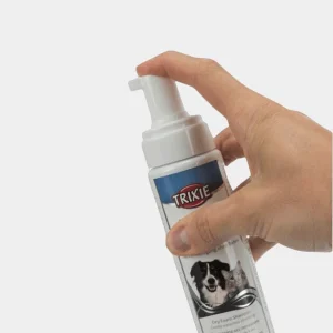Champú en Seco para Perros Trixie – Higiene Canina Innovadora Mano sujetando un bote de Champú en Seco Trixie para perros, mostrando el dispensador de espuma fácil de usar para la limpieza sin agua