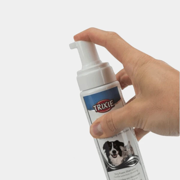 Mano sujetando un bote de Champú en Seco Trixie para perros, mostrando el dispensador de espuma fácil de usar para la limpieza sin agua