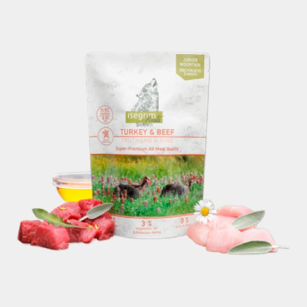 Bolsa de alimento super premium Isegrim Junior Mountain para cachorros con carne de pavo y ternera, rodeado de ingredientes frescos y hierbas del monte