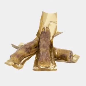 Tres patas de jamón para perros envueltas individualmente en papel dorado, proporcionando un snack rico en proteínas y beneficioso para la salud dental canina
