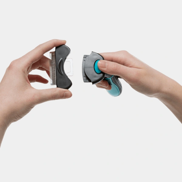 Manos mostrando una carda profesional para perros diseñada para eliminar el pelo muerto con facilidad, destacando su mecanismo de cuchillas finas y mango ergonómico