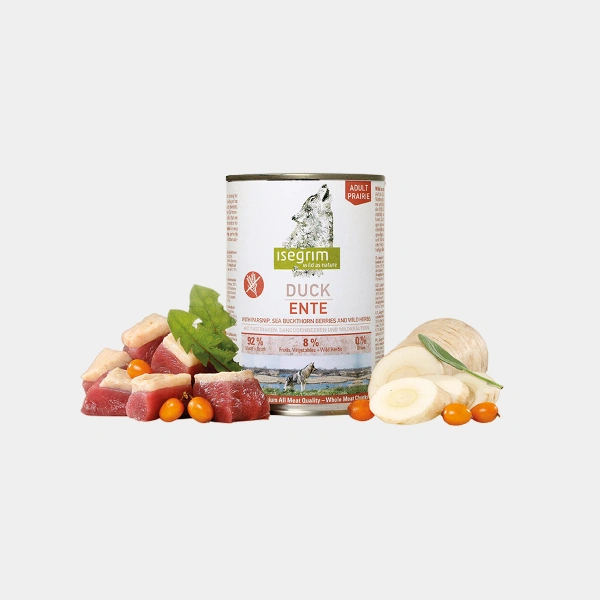 Lata de comida Isegrim para perros con ingredientes naturales a su alrededor, mostrando trozos de pato fresco, chirivía y bayas de espino amarillo, destacando un alimento super premium para perros basado en pato de alta calidad y receta inspirada en la naturaleza