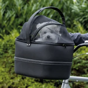 Perro asomando la cabeza en una cesta de viaje negra para bicicleta, un accesorio esencial para viajar con perros, asegurado al manillar y listo para la aventura