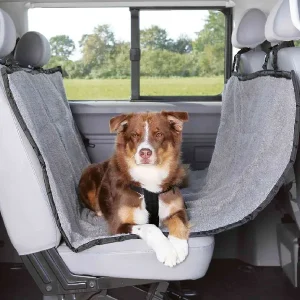 Funda Protectora de Coche para Perros – Confort y Limpieza en Viajes Perro tranquilo y seguro sentado en el asiento trasero de un coche equipado con una funda protectora de coche para perros de color gris, demostrando la comodidad y protección que ofrece