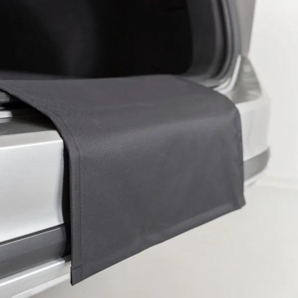 Detalle de una funda de maletero para perros extendida sobre el parachoques de un vehículo, protegiendo contra arañazos y suciedad