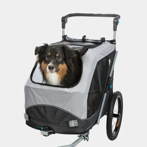 Un perro feliz asomándose desde un remolque de bicicleta para perros gris y negro con detalles reflectantes, listo para acompañarte en un emocionante paseo ciclista