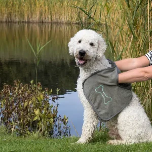 Perro siendo secado con una toalla de microfibra en color gris con diseño de hueso, ideal para secado rápido y eficiente después de actividades al aire libre