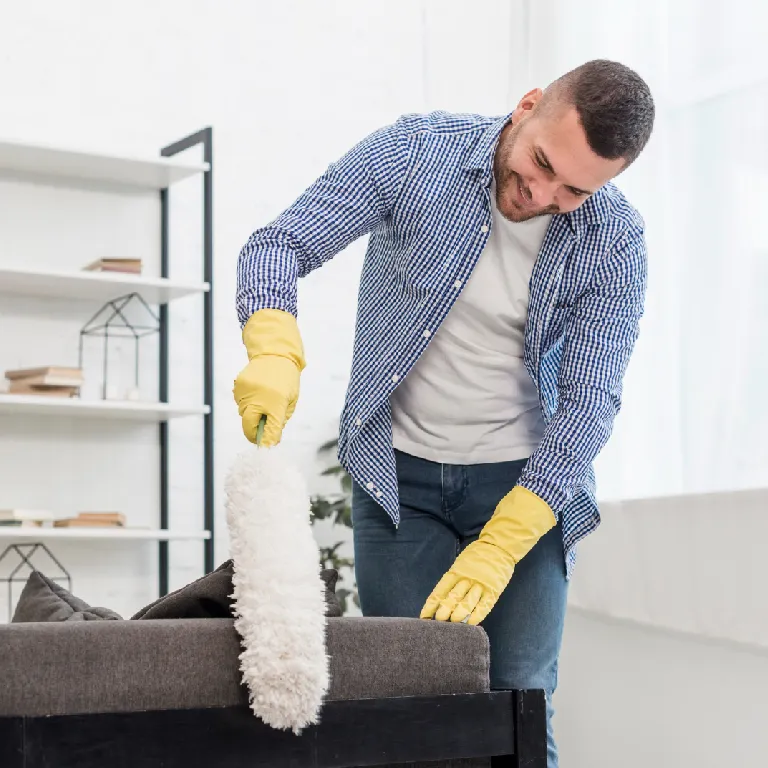 persona limpiando sofá con mopa y guantes amarillos